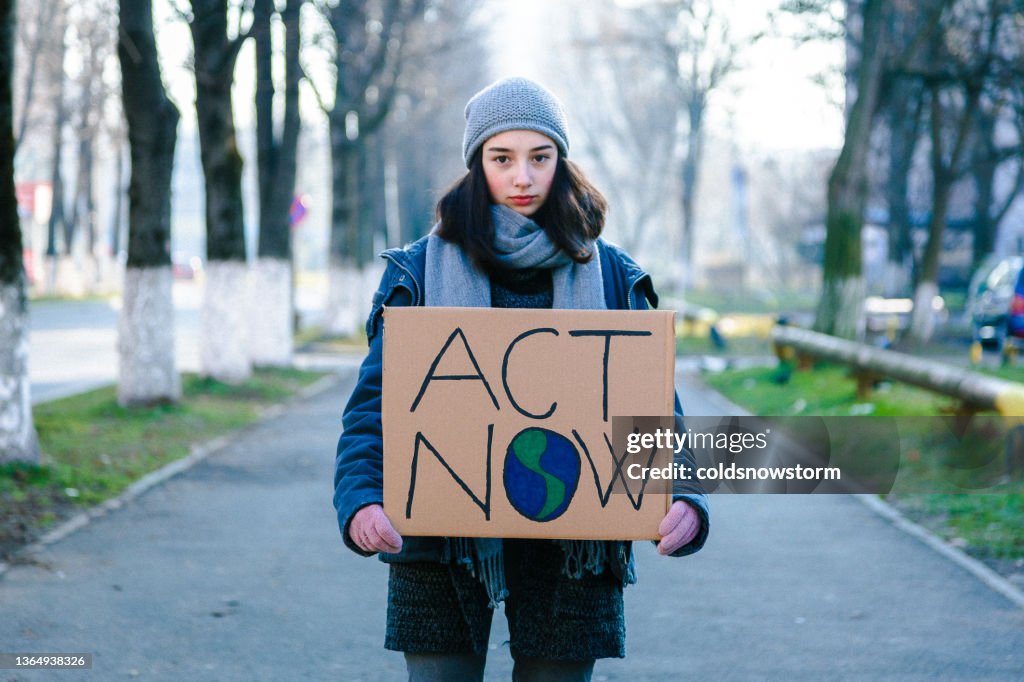 Joven activista sosteniendo cartel de protesta contra el cambio climático