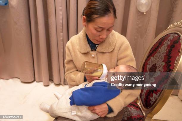 a young grandmother is nursing a baby. - 哺乳瓶 個照片及圖片檔