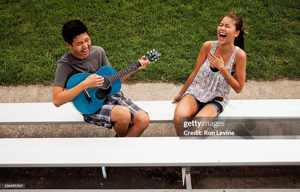 Teen boy and girl laughing with guitar