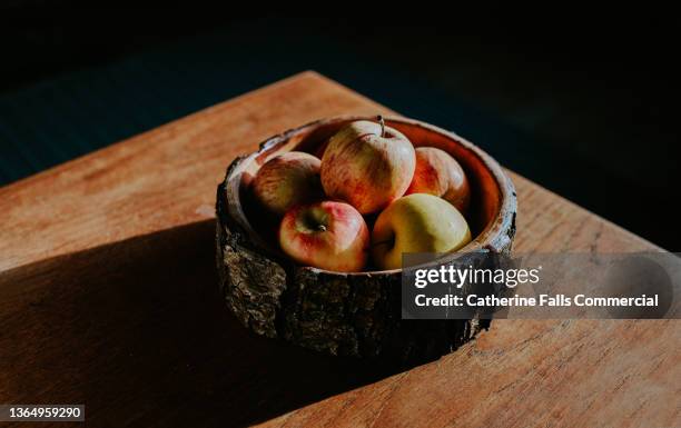 simple image of a rustic wooden fruit bowl containing red apples - fruit bowl stock pictures, royalty-free photos & images