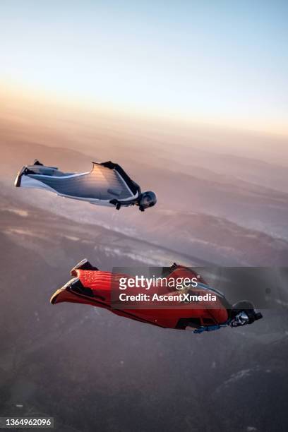 wingsuit fliers soar above swiss mountain landscape - parachute jump stockfoto's en -beelden