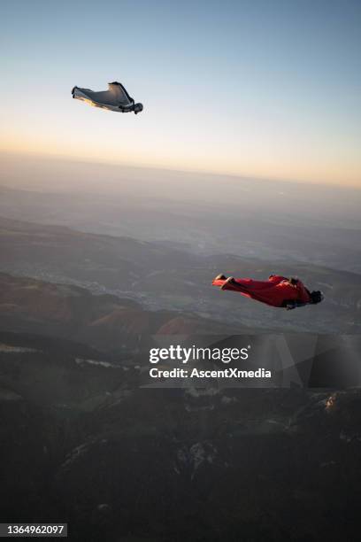 wingsuit fliers soar above swiss mountain landscape - wing suit stock pictures, royalty-free photos & images