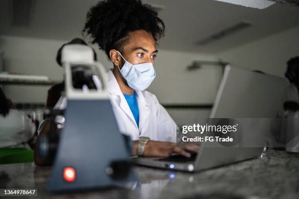 jovem estudando em laboratório usando laptop na universidade - usando máscara facial - educational subject - fotografias e filmes do acervo