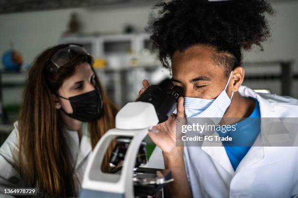 colegas estudando em uma microscopia de laboratório na universidade - usando máscara facial - edifício público - fotografias e filmes do acervo