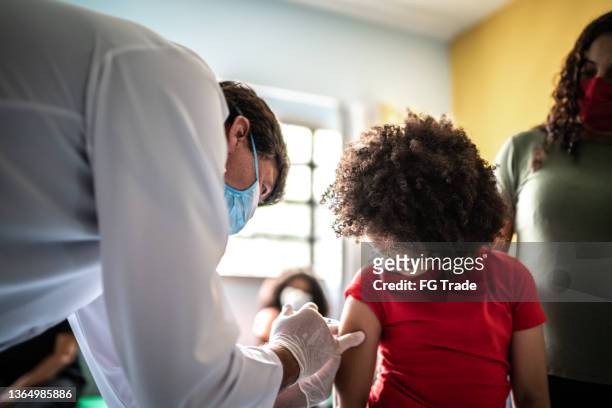 child girl getting vaccinated with her mother in vaccination center - vaccination center stock pictures, royalty-free photos & images
