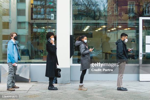 people standing in a line at temperature checkpoint outside office building - temperature checkpoint stock pictures, royalty-free photos & images