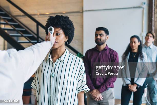 woman going through thermal body temperature checkpoint at office - social distancing in office stock pictures, royalty-free photos & images