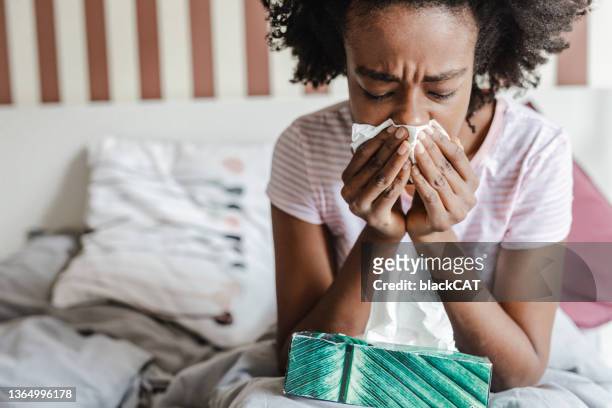 Woman with flu in bed blowing nose