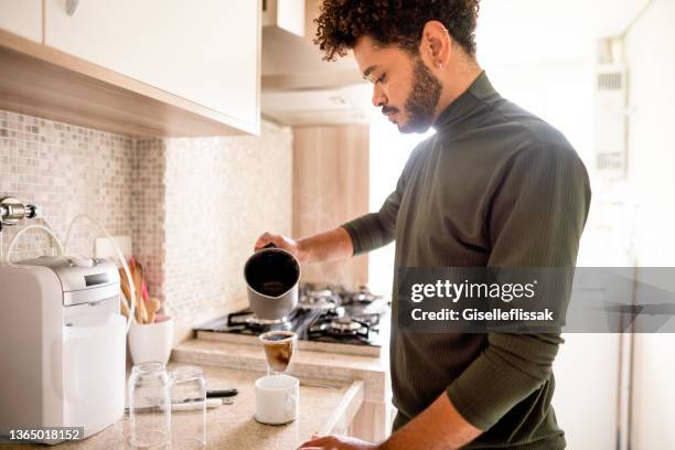 junger mann kocht frisch gebrühten kaffee zu hause - filterkaffee stock-fotos und bilder