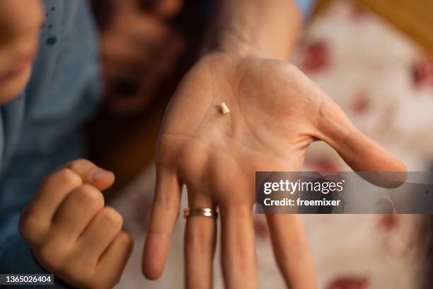 woman holding son's milk teeth in hand - tooth fairy stock pictures, royalty-free photos & images