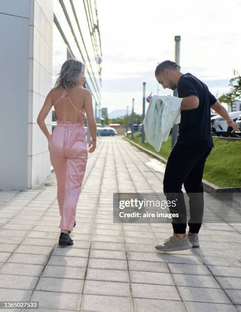 heterosexual couple walking on the external sidewalks of the office building back view - white jump suit stock pictures, royalty-free photos & images