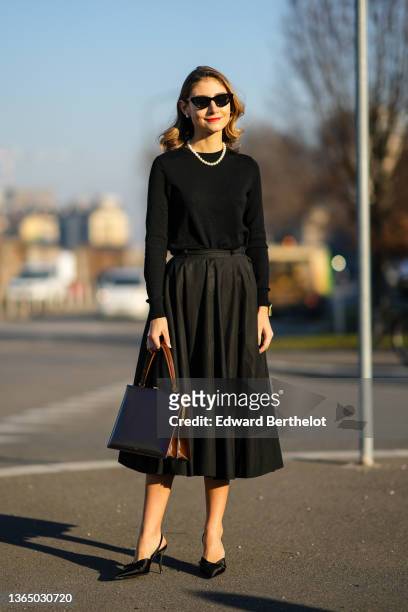 Jenny Walton wears sunglasses, a pearl beaded necklace, a black pullover, a brown rectangular briefcase shaped leather bag from Celine, a black...