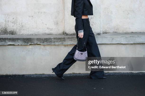 Caroline Daur wears black suit flared pants, a shiny Prada Cleo bag with metallic silver inserted pearls, black leather pointed shoes with kitten...