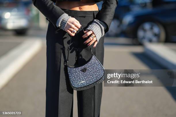 Caroline Daur wears black suit flared pants, a shiny Prada Cleo bag with metallic silver inserted pearls, black leather pointed shoes , outside the...