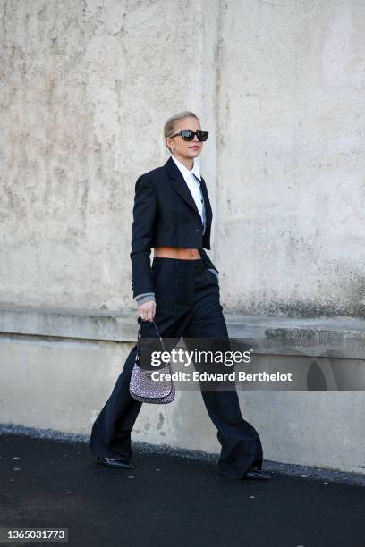 Caroline Daur wears sunglasses from YSL Saint-Laurent, earrings, a white cropped shirt, a black cropped blazer jacket, a gray wool ribbed cardigan,...