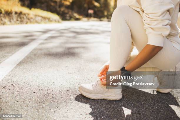 woman's hands tying shoes before running or jogging outdoors - chaussures blanches photos et images de collection