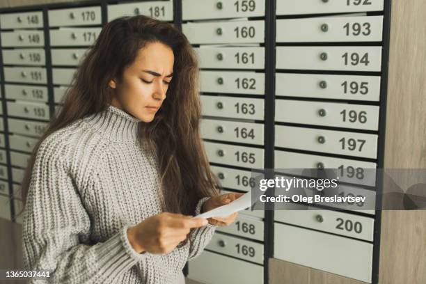 upset and stressed woman near post box disappointed by bad news and bills from letter mail - answering door stock pictures, royalty-free photos & images