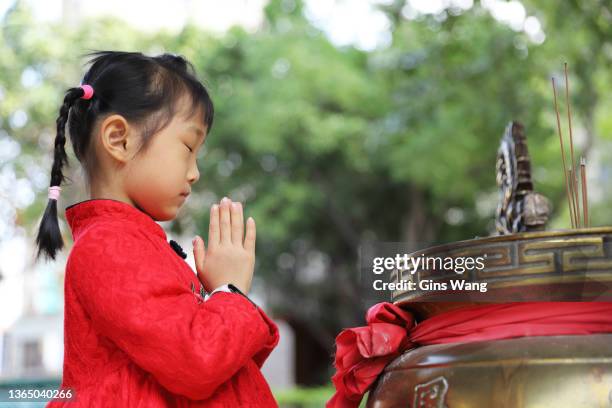 dos chicas gemelas asiáticas que llevan cheongsam hacen una visita de año nuevo ante un templo. - niños orando fotografías e imágenes de stock