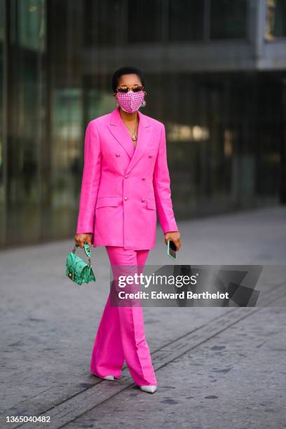 Tamu McPherson wears sunglasses, a golden necklace, a pink and white checked gingham pattern protective face mask, a bold pink double-breasted...