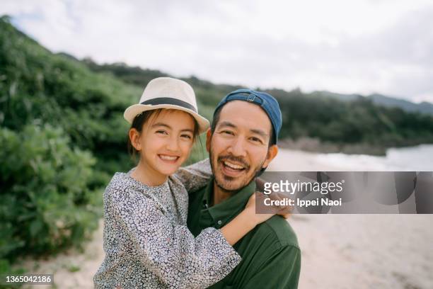 father and young daughter embracing on beach, japan - beautiful japanese girls stock pictures, royalty-free photos & images