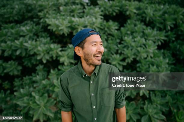 portrait of cheerful japanese man with cap - mirar-hacia-el-otro-lado fotografías e imágenes de stock
