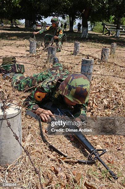 An Indonesia military cadet crawls on his hands and knees in an attempt to cross a wired path at Indonesia Navy Academy August 30, 2002 in Surabaya,...