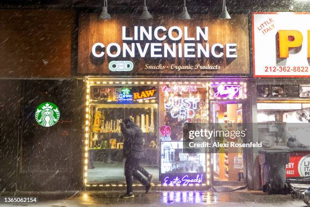 Man walks out of convenience store through the snow during Winter Storm Izzy on January 16, 2022 in New York City. New York City cases have recently...