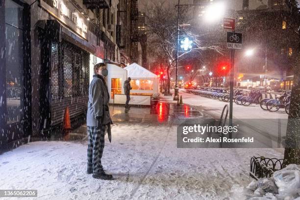 Man in pajamas stands in the snow during Winter Storm Izzy on January 16, 2022 in New York City. New York City cases have recently decreased despite...