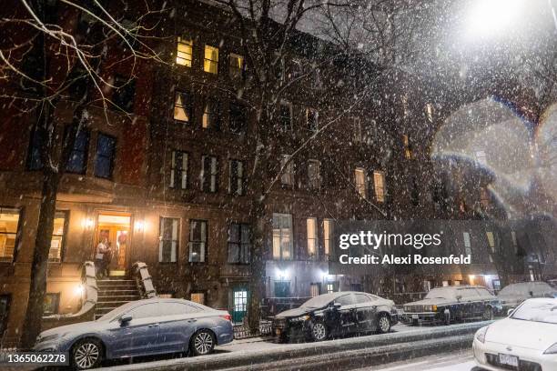 Couple embrace on a stoop in the snow during Winter Storm Izzy on January 16, 2022 in New York City. New York City cases have recently decreased...