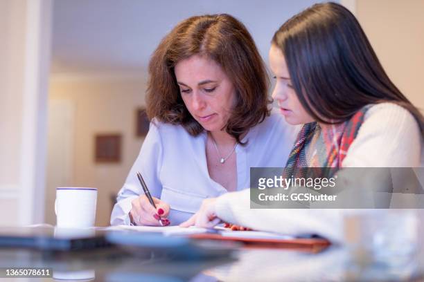 mother signing paperwork with her daugther for their new home - budget reconciliation stock pictures, royalty-free photos & images