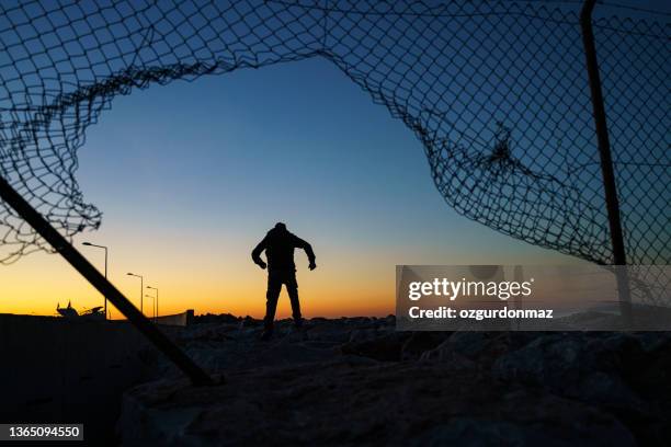 refugee man running behind fence - refugee silhouette stock pictures, royalty-free photos & images