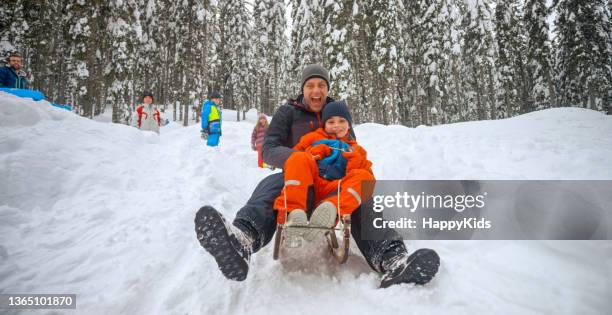 father and son tobogganing on snowy hill - tobogganing 個照片及圖片檔