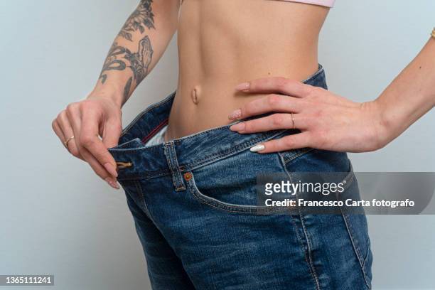 young woman losing weight - perder peso fotografías e imágenes de stock
