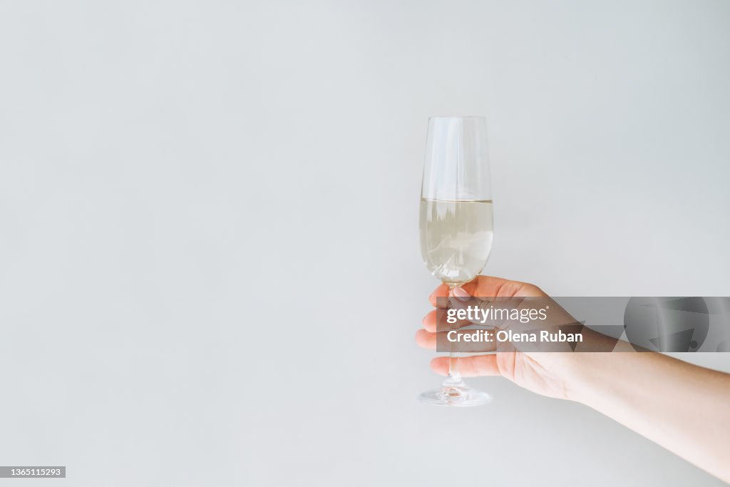 Female hand holding champagne flute.