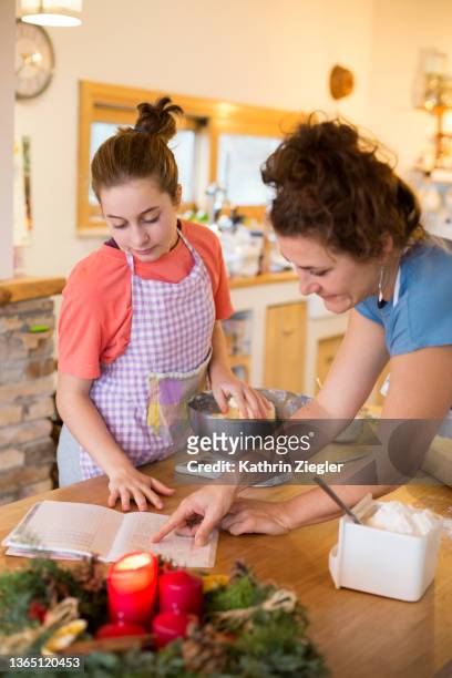 mother and daughter baking together, looking at recipe - baking reading recipe stockfoto's en -beelden