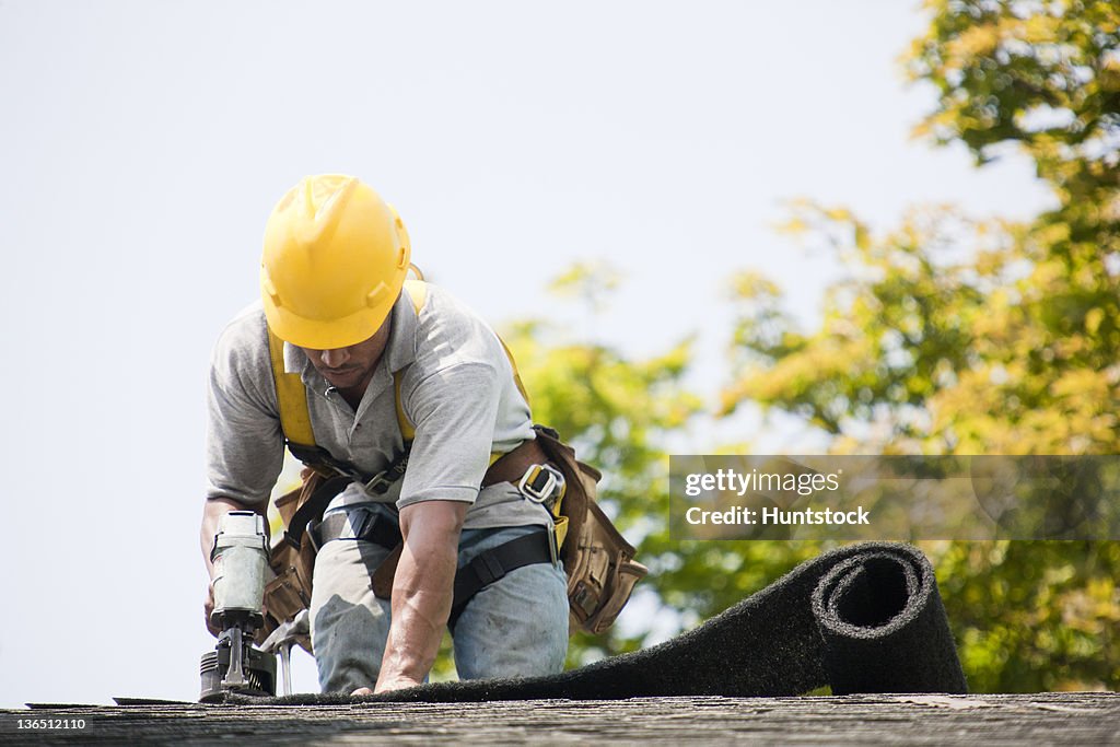Roofer working on shingling a new roof