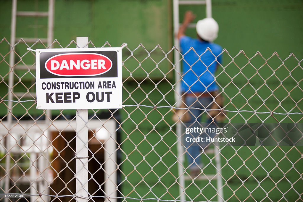 Keep Out sign in front of a carpenter installing windows