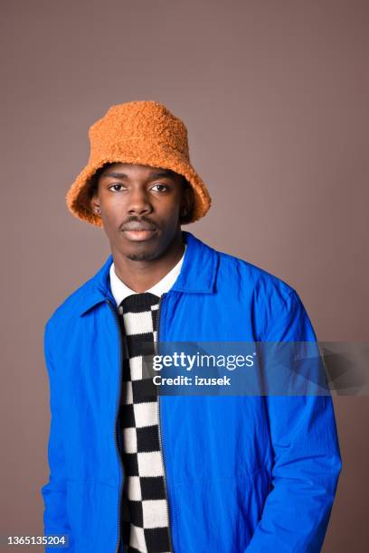 confident young man against brown background - bucket hat stock pictures, royalty-free photos & images