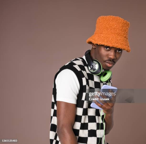 confident young man against brown background - bucket hat stock pictures, royalty-free photos & images