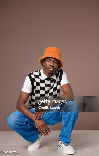 confident young man against brown background - lichaamshouding stockfoto's en -beelden