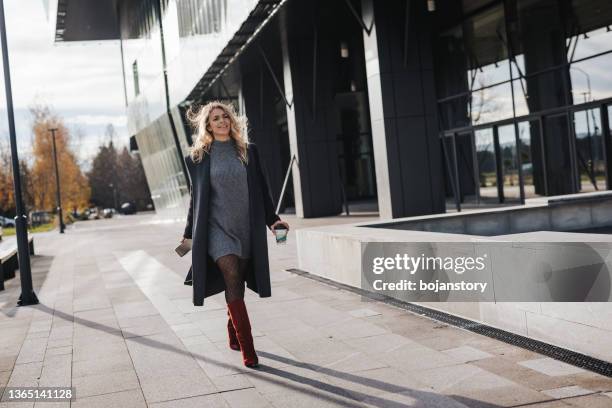 jeune femme d’affaires marchant avec un gobelet en papier à emporter à l’extérieur - winter dress photos et images de collection