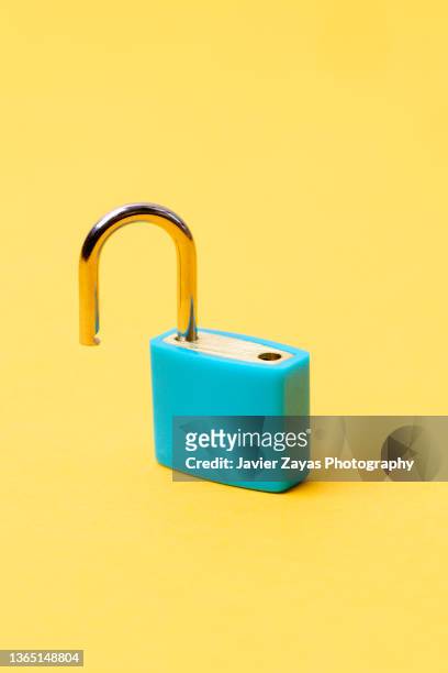 open blue padlock on yellow background - cerrar con llave fotografías e imágenes de stock