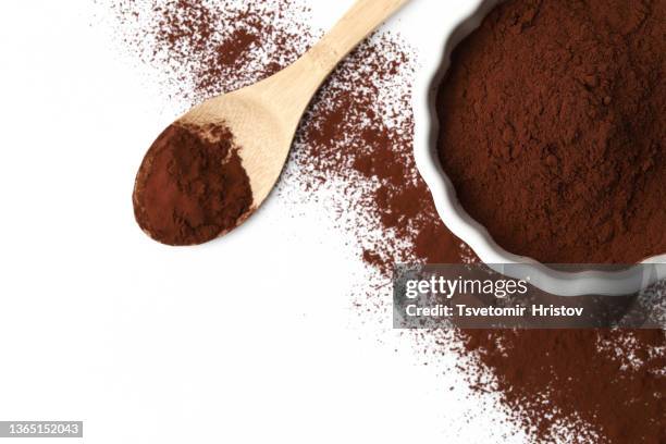 cocoa powder in white bowl and wood spoon isolated on white background. top view. flat lay. - kakaopulver stock-fotos und bilder