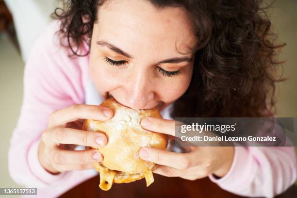 young woman eating tasty burger - pyjamas stock pictures, royalty-free photos & images