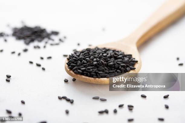 black sesame seeds in a wooden bowl on a white background - sesame stock pictures, royalty-free photos & images
