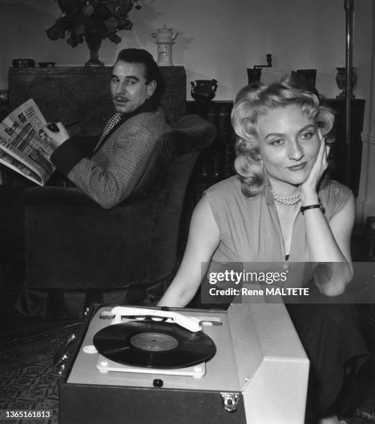 Couple dont le mari lit France-Soir et la femme écoute un disque sur une platine vinyle, en 1955.