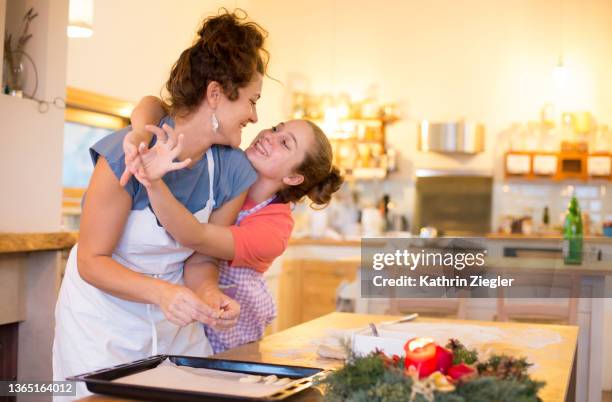 mother and daughter having fun, making christmas cookies together - italian mother kitchen stock pictures, royalty-free photos & images