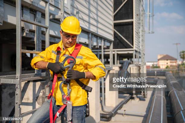 worker putting on safety harness - safety harness stockfoto's en -beelden