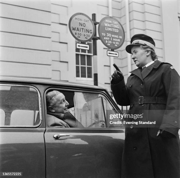 Mrs Elizabeth Golding, a female traffic warden, admonishes a driver next to a 'No Waiting' sign, UK, 3rd April 1964.