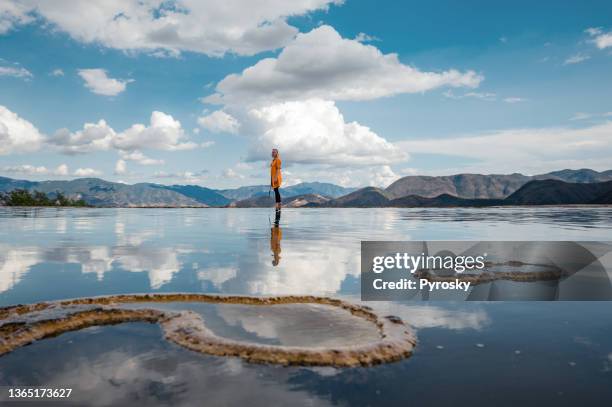 a woman stands on the edge of a natural infinity pool with a breathtaking mountains view - majestic waterfall stock pictures, royalty-free photos & images